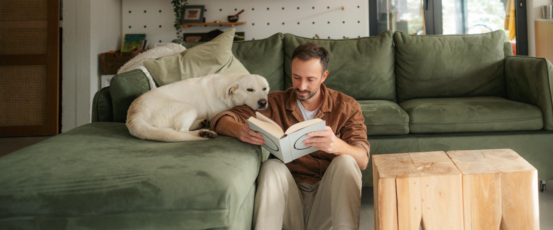 Man reading a book with his dog.